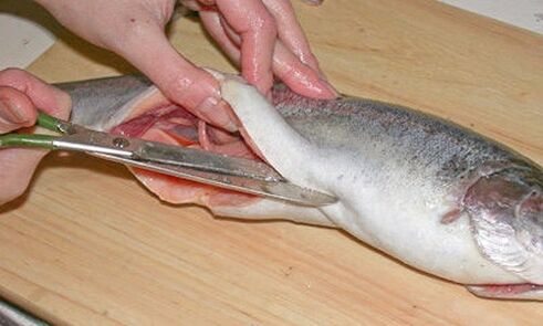 Cortar el pescado con cuidado en una tabla de cortar personal protege contra la infección por parásitos
